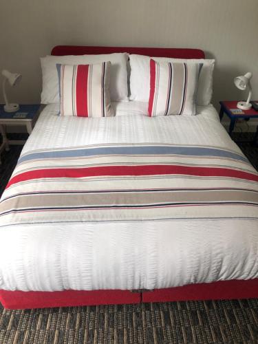 a large bed with red and white sheets and pillows at Tredara Bed & Breakfast in Truro