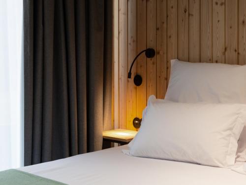 a bed with a white pillow and a wooden wall at Landescape Furnas in Furnas