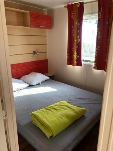 - une chambre dotée d'un lit avec un oreiller vert dans l'établissement Mobilhome A16 Au phare d Opale, à Le Portel