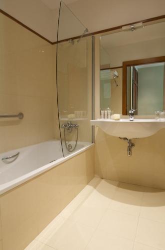a bathroom with a shower and a sink and a tub at Hotel Manantial in Caldes de Boi
