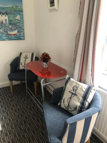 a room with two chairs and a table with a red table at Tredara Bed & Breakfast in Truro