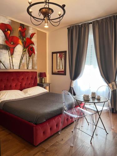 una camera con letto rosso, tavolo e finestra di Residenza Anton Doni a Firenze