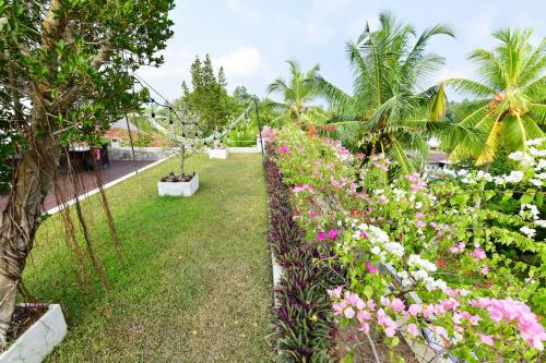 a garden with pink and white flowers and palm trees at TROPICAL HOUSE - Jungleside Villa in Hikkaduwa
