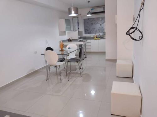 a white kitchen with a dining table and chairs at Departamento 1 dormitorio, Saenz Peña. in Santiago del Estero