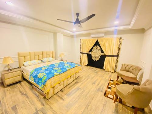 a bedroom with a bed and a chair at Holidazzle Serviced Apartments Bahria Town in Rawalpindi