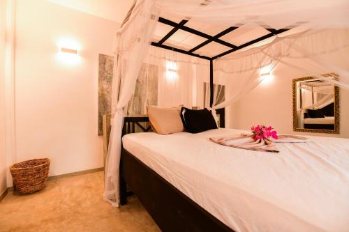 a bedroom with a large white bed with flowers on it at TROPICAL HOUSE - Jungleside Villa in Hikkaduwa