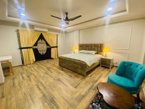 a bedroom with a bed and a blue chair at Holidazzle Serviced Apartments Bahria Town in Rawalpindi