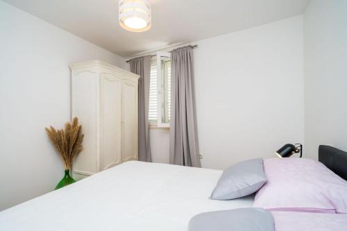 a bedroom with a white bed and a window at Apartment Mioć in Dubrovnik
