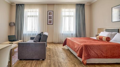 Aisha Bibi Hotel & Spa في أستانا: غرفة فندقية بسرير كبير واريكة