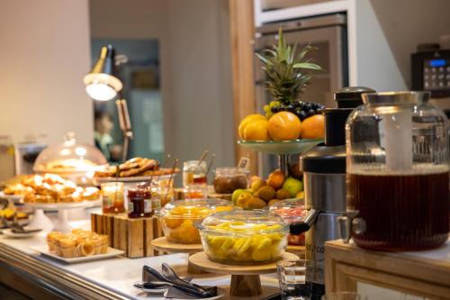 a buffet with fruit and other food on a counter at Hôtel et Spa La Villa K - Basel Airport in Saint-Louis