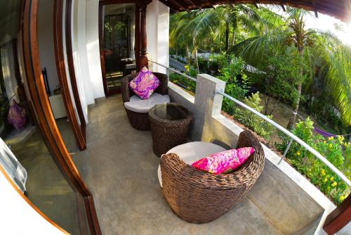 a balcony with two wicker chairs and a balcony with plants at TROPICAL HOUSE - Jungleside Villa in Hikkaduwa
