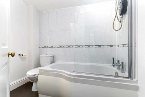 a white bathroom with a tub and a toilet at Haulfryn Apartment in Conwy