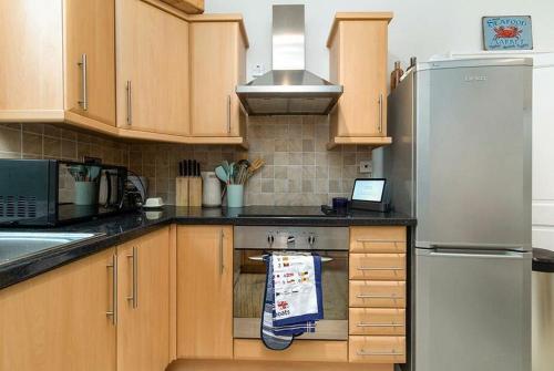 a kitchen with a refrigerator and a towel hanging on the oven at Haulfryn Apartment in Conwy
