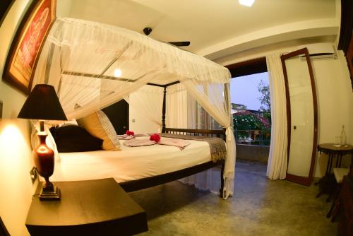 a bedroom with a bed with a canopy at TROPICAL HOUSE - Jungleside Villa in Hikkaduwa
