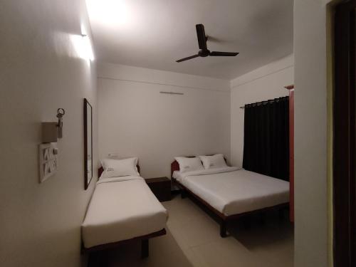 a room with two beds and a ceiling fan at Ashray Residency in Vānivilāsa Puram