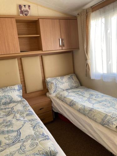 a small bedroom with two beds and a window at Caravan Skegness GB 148 in Chapel Saint Leonards