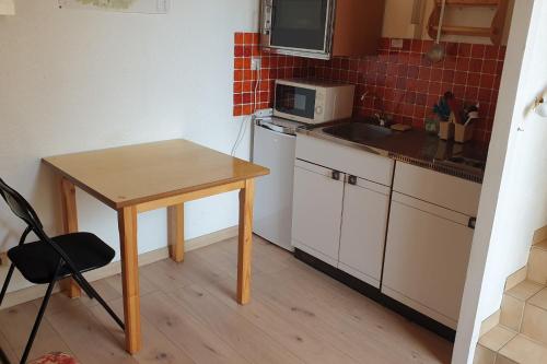 une petite cuisine avec une table et un four micro-ondes dans l'établissement Joli Studio Chamechaude, à Saint-Pierre-de-Chartreuse