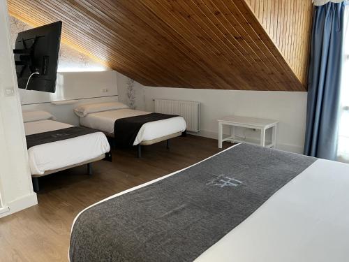 a hotel room with two beds and a tv at Hotel Avelina in Cangas de Onís