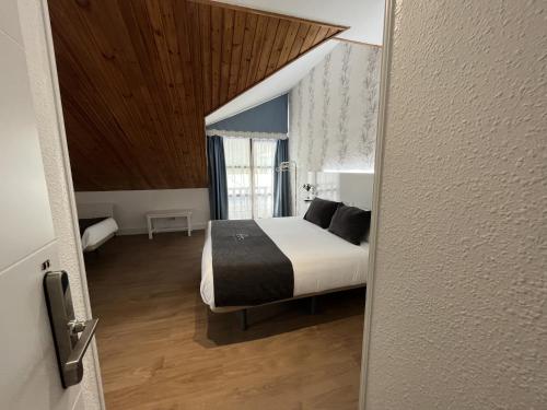 a bedroom with a bed and a wooden ceiling at Hotel Avelina in Cangas de Onís