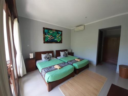 a bedroom with two twin beds and a table at Nugraha Guest House 2 in Ubud