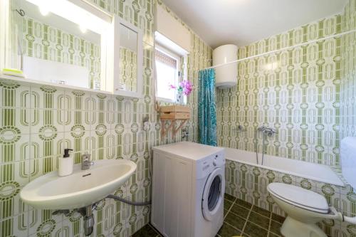 a bathroom with a sink and a washing machine at Fia 70s Beach Apartment in Rab