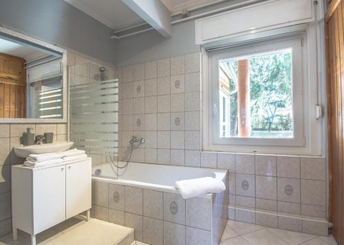 uma casa de banho com uma banheira, um lavatório e uma janela em 101 Apartman Agárd,Török Bálint utca 101 em Agárd