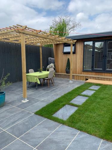 a patio with a green table and a wooden pergola at Lindas LODGE Free PARKING air con plus provisions included in Hove