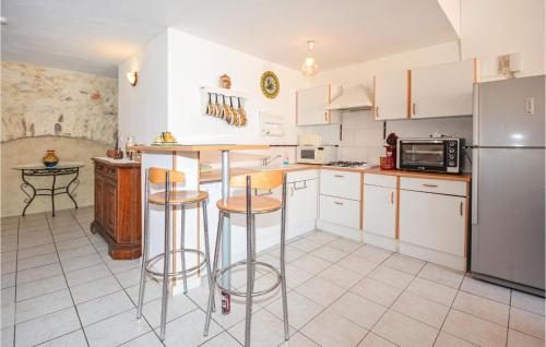 een keuken met witte kasten en barkrukken bij 2 Bedroom Pet Friendly Home In Cessenon Sur Orb in Cessenon