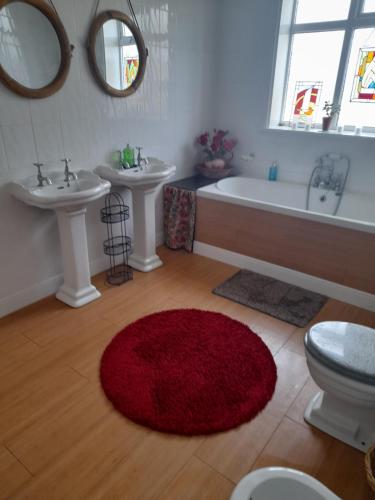łazienka z 2 umywalkami, wanną i czerwonym dywanem w obiekcie Bastwick House B&B w mieście Great Yarmouth