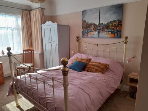 a bedroom with a bed with purple sheets and a painting at Bastwick House B&B in Great Yarmouth