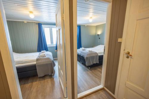 a small room with two beds and a mirror at The Tide - Rorbuer in Sørvågen