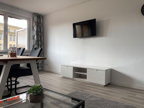 a living room with a table and a tv on the wall at Moderne Studios im Herzen von Osnabrueck in Osnabrück