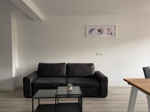 a living room with a leather couch and a table at Moderne Studios im Herzen von Osnabrueck in Osnabrück