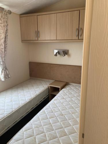 a small room with two beds and wooden cabinets at Skegness B10 in Chapel Saint Leonards