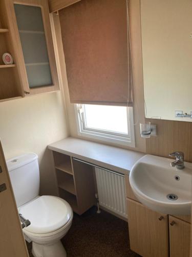 a small bathroom with a toilet and a sink at Skegness B10 in Chapel Saint Leonards