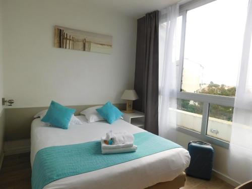 a bedroom with a bed with blue pillows and a window at Résidence New Rochelle in La Rochelle
