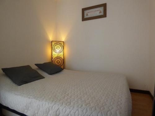 um quarto com uma cama branca e uma luz sobre ela em Appartement T2 coquet, proche mer, Narbonne Plage em Narbonne Plage