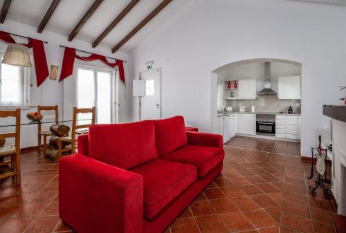 a living room with a red couch and a kitchen at Monte do Giestal - Casas de Campo & Spa in Abela