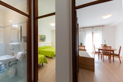 a room with a green bed and a dining room at Holiday Appartamenti in Grado
