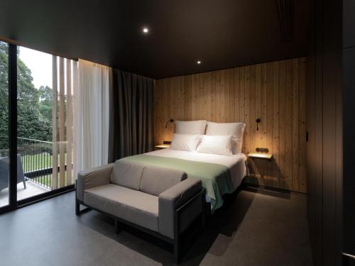 a bedroom with a bed and a chair and a window at Landescape Furnas in Furnas