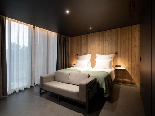 a bedroom with a bed and a chair and window at Landescape Furnas in Furnas