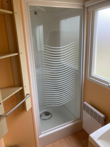 a glass shower in a bathroom next to a window at Camping l’r pur in Saint-Vincent-sur-Jard