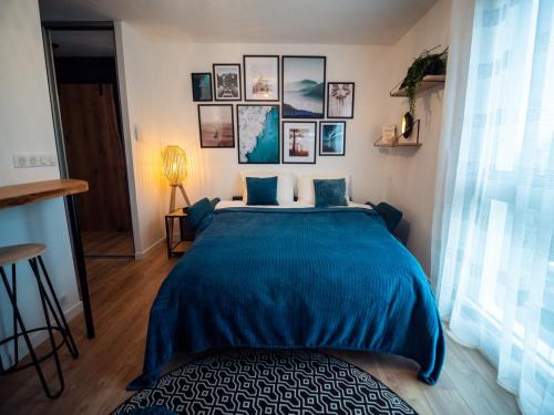 um quarto com uma cama azul com fotografias na parede em HESPERIE Thermes em Chamalières