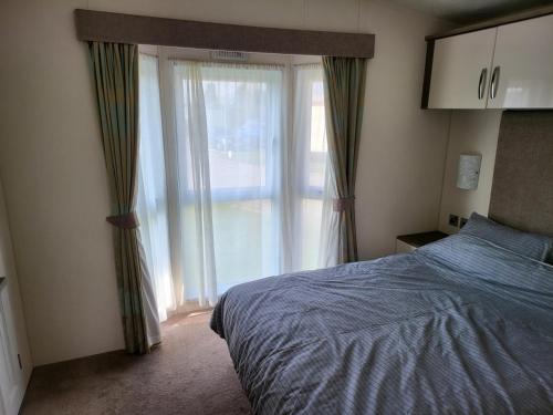 a bedroom with a bed and a large window at 2BR-Sleeps6-Fireplace-Parking-Patio-Seaside in Clacton-on-Sea