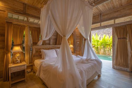 a bedroom with a bed with a mosquito net at Wana Shanti Villa in Bringkit