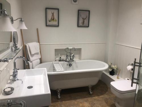 a white bathroom with a tub and a toilet at The Kings Head in Whiteparish
