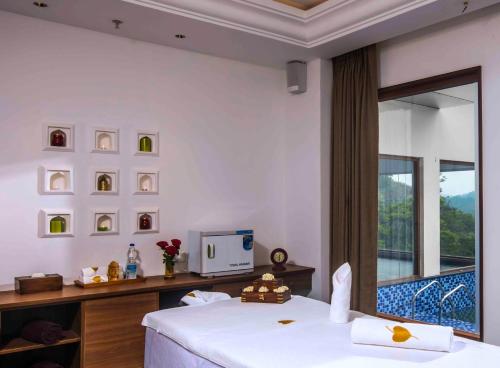a bedroom with a bed and a tv and a balcony at GReaT Trails Wayanad by GRT Hotels in Wayanad