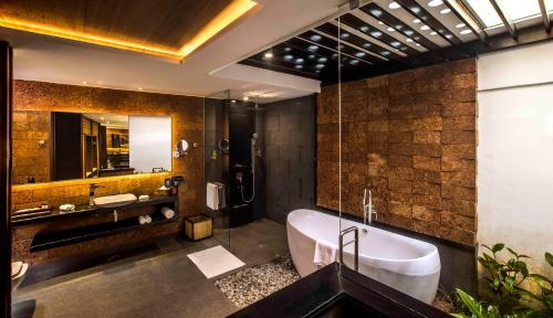 a bathroom with a tub and a sink and a mirror at GReaT Trails Wayanad by GRT Hotels in Wayanad