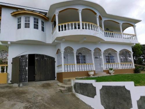 a large white house with a balcony at Remarkable 2-Bed Villa in Fair Prospect Sea View in Port Antonio