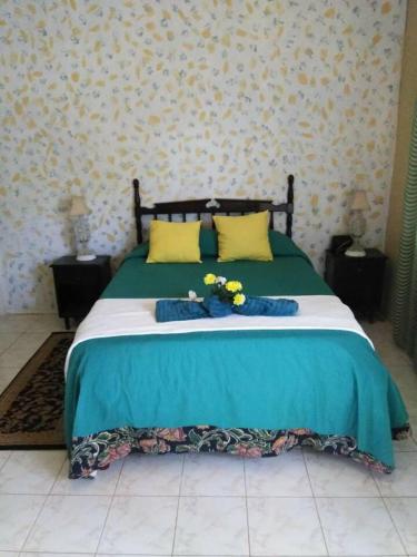a green bed with yellow pillows and flowers on it at Remarkable 2-Bed Villa in Fair Prospect Sea View in Port Antonio